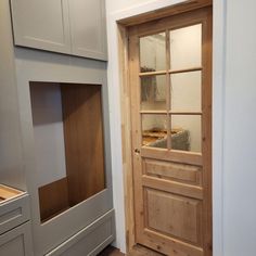 an empty room with a wooden door and built - in storage area next to it