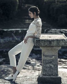 a woman sitting on top of a stone bench