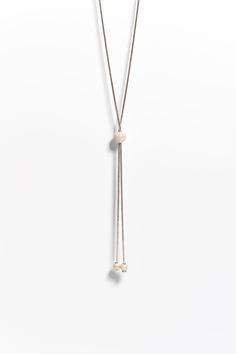 Add a touch of elegance and versatility to your jewelry collection with our Sterling Silver Lariat Layering Necklace. This stunning and unique necklace is expertly handcrafted from high-quality sterling silver, and features glistening silver beads that add a touch of shimmer and sparkle to any outfit. The lariat design of this necklace makes it perfect for layering with other necklaces, or for wearing alone as a statement piece, making it a versatile addition to your jewelry collection. Each nec Adjustable White Lariat Drop Necklace, White Adjustable Lariat Drop Necklace, Elegant Lariat Beaded Necklaces With Adjustable Chain, Adjustable Single Strand Lariat Necklace With Round Beads, Elegant Lariat Beaded Necklace With Adjustable Chain, Minimalist Silver Jewelry With Dangling Beads, Adjustable Lariat Necklace With Dangling Round Beads, Elegant Adjustable Lariat Necklace With Round Beads, Adjustable White Gold Lariat Necklace