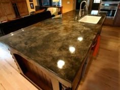 a large kitchen island with granite counter tops and wooden flooring in the middle of a living room