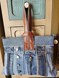 an old pair of jeans hanging on a door handle with a leather purse in the pocket