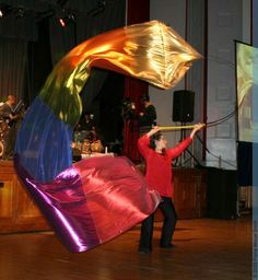 a man holding a large kite on top of a wooden floor next to a stage