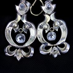 "Georgian silver topped 14k gold drop earrings with over 5 carats of diamonds feature a combination of old mine cut and rose cuts. The stunning earrings have been preserved for nearly 200 years. One has been repaired at some point in its history of ownership. The bottom flourish was reattached and the top of the pendulous was reinforced and reattached. See detailed imagery of repairs. These have not been cleaned by us in case of foil backings on non open backed stone mountings, which were preval Formal Rose Cut Diamond Chandelier Earrings, Formal Chandelier Earrings With Rose Cut Diamonds, Sterling Silver Single Cut Diamond Earrings For Evening, Sterling Silver Earrings With Single Cut Diamonds For Evening, Formal Silver Chandelier Earrings With 17 Jewels, Victorian Style Hallmarked Earrings For Formal Occasions, Silver Diamond Chandelier Earrings Pierced, Formal Silver Rose Cut Diamond Earrings, Formal Victorian Hallmarked Earrings