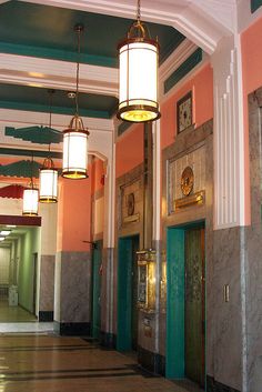 an empty hallway with two lamps hanging from the ceiling