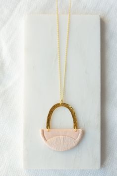 "This series of pendants were inspired by the landscapes we explored with our little ones in the summer. Rolling hills and peaks all to be found in Yorkshire. This small pendant is made from Blush cotton and is fully interfaced to provide support. I have stitched the edges and curved pattern using a matching Blush thread. This is suspended under a hammered brass arc and hangs from an 18\" chain of gold vermeil (sterling silver plated with 18ct gold). I have enamelled the brass arc to prevent tar Chain Of Gold, Embroidered Jewellery, Fiber Jewelry, Hammered Brass, Brass Necklace, Small Pendant, Rolling Hills, Etsy Fashion, Gold Vermeil