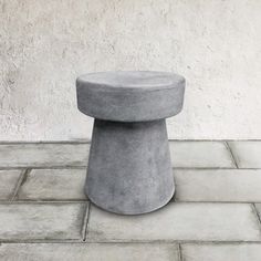 a concrete stool sitting on top of a tiled floor