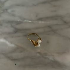 a gold ring sitting on top of a white marble counter with a pearl bead in the middle