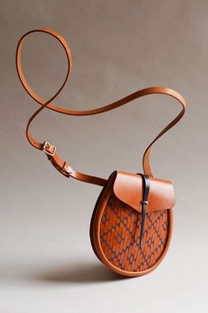 a brown leather bag with a strap hanging from it's shoulder and the handle is made out of wood