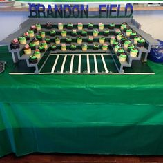 a table topped with cupcakes and cakes on top of a green table cloth