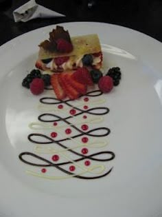 a white plate topped with a piece of cake and berries