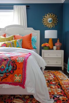 a bedroom with blue walls, white bedding and bright colored pillows on the bed