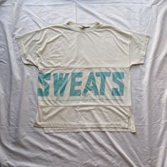 "Vintage 80s SWEATS dd Bi Chego white and blue t-shirt. Size medium, fits oversized. Single stitch. 65% polyester, 35% cotton. Flaws: One dark mark on the front. Note: Longer in back by like half an inch. Care: Machine washable. Measurements  Length: 24.5\" Width: 22\"" Sporty Boxy Fit Screen Print T-shirt, Sporty Boxy T-shirt With Screen Print, Oversized White Sweatshirt With Logo Print, White Drop Shoulder T-shirt With Graphic Print, Sporty Cotton T-shirt For Leisure, Hip Hop Oversized Slogan Tops, Oversized Hip Hop Tops With Slogans, Crew Neck Logo T-shirt For Loungewear, Oversized Crew Neck Top In Hip Hop Style