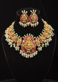 This exquisite necklace set showcases a beautifully crafted lord Krishna adorned with intricate etchings. The pendant, inspired by the lord of divine form radiates serenity and grace, evoking a sense of reverence and admiration, and is accompanied by equally stunning Krishna earrings. The necklace itself is adorned with Lord Krishna and peacock motifs, enhanced by embellished stones and dangling green beads. Note: This jewelry has no precious metals or stones.  Note: Some of the pics are close-u Spiritual Temple Necklace With Intricate Design For Celebrations, Spiritual Temple Necklace For Celebration With Intricate Design, Temple Jewelry Style Engraved Necklace For Celebration, Spiritual Festive Necklace With Intricate Design, Elegant Hand Set Jewelry For Rituals, Spiritual Jewelry With Intricate Design For Celebrations, Festive Jewelry With Intricate Design, Spiritual Necklace With Intricate Design For Festive Occasions, Engraved Temple Jewelry Necklace For Celebrations