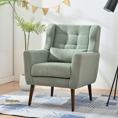 a green chair sitting on top of a wooden floor next to a potted plant