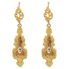 For pierced ears. Earring in 18 karat yellow gold. Antique dangle earings, they are constituted of an openwork plant pattern which holds in pampille a long pendant whose center is made of brown and white enamelled decorations. Height : 5 cm, width : 1.2 cm, thickness : 1.6 mm. Total weight of the jewel : 6,5 g approximately. Authentic antique jewel - Work of the XXth century, in the spirit of the antique jewels of the XIXth century. Our opinion : Well in the spirit of the XIXth century, these antique earrings are flat and easy to wear. Retro Engagement Rings, Outfit Pieces, Retro Ring, Gold Dangle Earrings, Plant Pattern, Antique Earrings, Long Pendant, The Jewel, Yellow Gold Earring