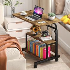 a laptop computer sitting on top of a wooden table next to a couch and window