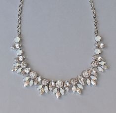 "A stunning new necklace made entirely using Swarovski crystals and elements. The necklace is a cluster style, with various shaped and sizes of stones. There are larger marquise clusters, underneath embellished flower links, each set with teeny crystals. Stones range in color from crystal clear, crystal moonlight, white opal, white pearl, and more. Each stone is painstakingly set by hand, and either prong or pave set. Jeweled portion of the necklace measures 8\" wide, and connects to rhodium pla White Crystal Rhinestone Necklace For Anniversary, White Rhinestone Wedding Necklace With Sparkling Stones, White Sparkling Rhinestone Necklace For Wedding, Crystal Bridal Necklace With Stones For Wedding, Sparkling White Rhinestone Necklace For Wedding, White Sparkling Crystal Bridal Necklace, White Sparkling Bridal Necklace For Anniversary, Wedding Bridal Crystal Necklace With Stones, Sparkling White Bridal Necklace For Anniversary