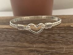 This is a handcrafted bangle/bracelets. It is designed with an oval shape to ensure a proper fit. It is the perfect gift for mothers, sisters, birthdays, daughters, and lovers. This is a simple classy bracelets.  It is  5mm in wide, handcrafted wire-wrapped bangle bracelet, wire wrapped in sterling silver. A dainty, elegant bracelet that can be used as a statement piece. All my materials are14K gold-filled and/or sterling silver and are purchased from reputable jewelers. These bracelets will not tarnish. No plated materials. Wear it every day!   This bracelet can be ordered in 6, 7, 8, or 8.5 and inches. The most common size is 7.5. If this does not match your needs please contact me. When measuring for the bracelet, measure your wrist size.  order your snug wrist size, not your bracelet s Wire Wrapped Bangle Jewelry For Anniversary, Adjustable Sterling Silver Heart Bracelet For Anniversary, Silver Hand Wrapped Bracelets For Friendship, Adjustable Handmade Heart Bracelet, Handmade Silver Adjustable Heart Bracelet, Handmade Adjustable Silver Heart Bracelet, Adjustable Wire Wrapped Bracelet For Anniversary, Adjustable Handmade Silver Heart Bracelet, Gift Wire Wrapped Round Bangle