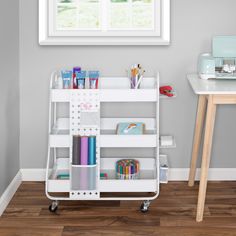 a white cart with books and stationery on it next to a desk in a room