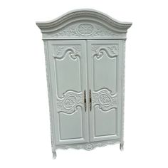 a white armoire with ornate carvings on it