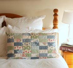 a bed with white sheets, pillows and a wooden headboard on top of it