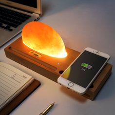 a cell phone sitting on top of a wooden stand next to a light that is turned on