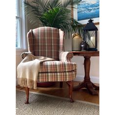 a chair with a blanket on it next to a table and potted palm tree