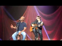 two men on stage playing guitars and singing