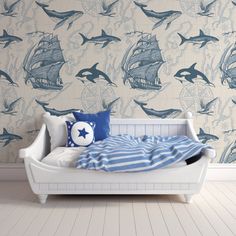 a white bed sitting in front of a wall with dolphins on it