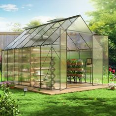 a green house in the middle of a yard with flowers and plants growing inside it