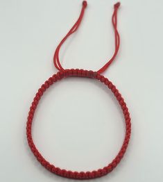 a red string bracelet on a white surface