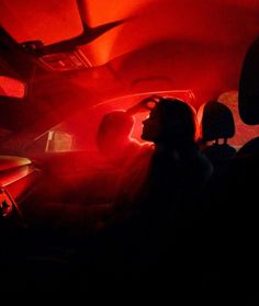 two people sitting in the back seat of a car with red light shining on them