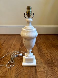 a white lamp sitting on top of a hard wood floor next to a charger