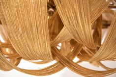 several strands of gold colored string hanging from a ceiling