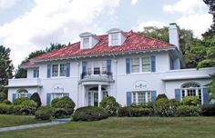 a large white house with blue shutters and red roof