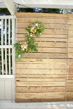 a wooden fence with flowers on it and some plants growing out of the top part