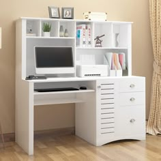 a white computer desk with drawers and a monitor on it's stand next to a window