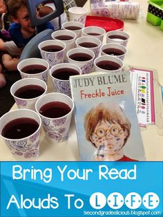 children are sitting at a table with books and cups filled with liquid to drink from them