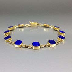 Timeless bracelet blue Lapis Lazuli and solid 18K gold. Unique gift for her, girlfriend, wife, September and December birthstone, 9 year anniversary. The bracelet combines simplicity and elegance in design and trough the combination of the blue Lapis Lazuli with the warm 18K gold. This beautiful Bracelet is worked with the technique of inlay, which means the stone is worked seamlessly into the 18K gold with a full back gold. All our stones are natural stones and our jewelry is handmade, slight differences in color and size may occur. Our inlay work is made with real stone and NOT stone dust. Please note the size specifications! Stone size: 6 x 6 x 2mm weight: 11.7 g - 12.9 g     Carat: 7 Gold: 10.3 g - 11.5 g                               We try to make our photos in daylight and sunshine, Timeless Blue Round Bracelets, Blue Birthstone Bracelets In Fine Jewelry Style, Blue Birthstone Bracelets Fine Jewelry, Formal 14k Gold Bracelets With Bezel Setting, Classic Lapis Lazuli Yellow Gold Jewelry, Classic Yellow Gold Lapis Lazuli Jewelry, Classic Yellow Gold Jewelry With Lapis Lazuli, Rectangular Gemstone Bracelet In Yellow Gold, Rectangular Yellow Gold Bracelet With Gemstone