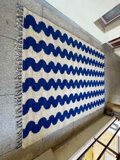 a blue and white rug hanging on the side of a wall next to a window