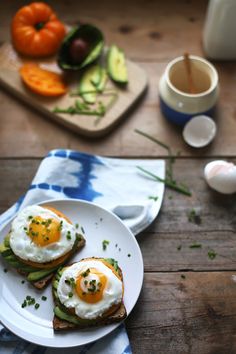 two eggs are on toast with avocado and tomatoes