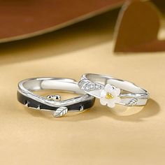 two wedding rings with flowers on them sitting on a table next to each other,