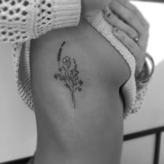 a black and white photo of a woman's back with flowers on her left side