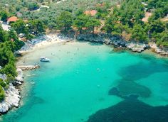 an aerial view of a beach with clear blue water and trees surrounding the area is shown from above