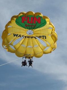 two people are parasailing in the sky with a parachute attached to their feet