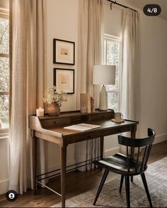 a desk with a lamp, chair and pictures on the wall in front of it