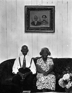 an old black and white photo of two people sitting on a couch