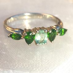 Genuine Green Kyanite & Chrome Diopside .925 Sterling Silver Ring. A Central Oval Kyanite Is Flanked By Pear & Marquise Natural Russian Diopside In This Limited Edition Piece Imported From The Uk. The Gemstones Were Ethically Sourced And Have Not Been Treated. Green Kyanite Is Much Less Common Than The Blue Variety, And Has A Soft Mint Or Seafoam Color That Can Appear To Glow The Way Paraiba Tourmaline Does. Chrome Diopside Is Only Mined A Few Months A Year, Because The Ground Is Frozen Much Of Classic Green Multi-stone Emerald Ring, Classic Green Tourmaline Jewelry, Green Gemstone Sterling Silver Birthstone Ring, Green Emerald Cut Multi-stone Jewelry, Silver Emerald Ring With Tourmaline Birthstone, Silver Emerald Ring With Accent Stones For May Birthstone, Green Multi-stone Rings For May Birthstone, Green Multi-stone Emerald Ring For May Birthstone, Green Multi-stone Jewelry For May Birthstone