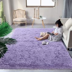 a woman sitting on the floor reading a book in front of a purple area rug