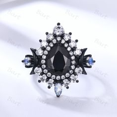 a black and white ring with clear stones on the center, surrounded by smaller blue crystals